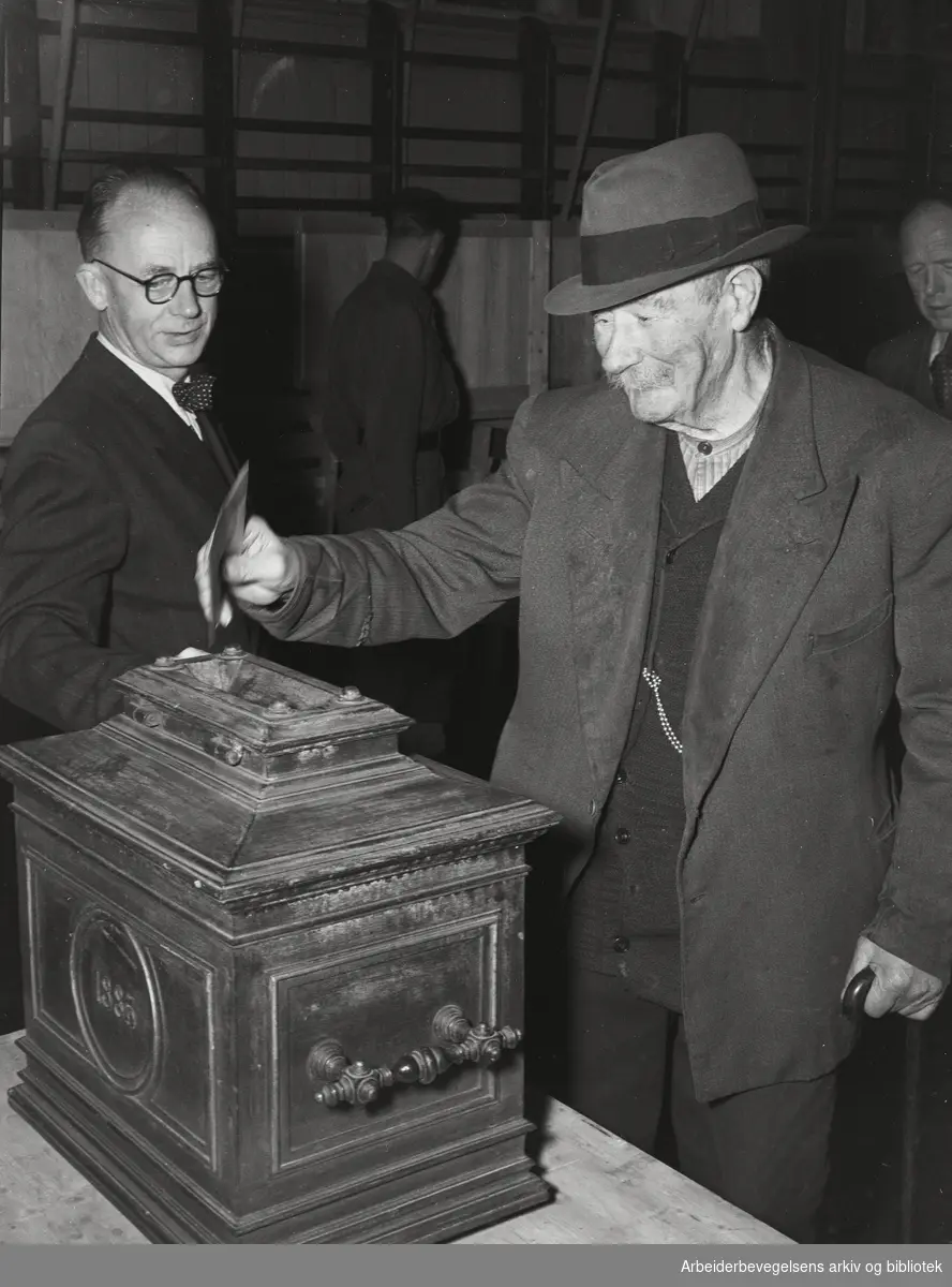 Stortingsvalget 1949 i og utenfor valglokalene. Eldre mann avgir sin stemme. Stemmeurne fra 1885. Antatt Vahl skole