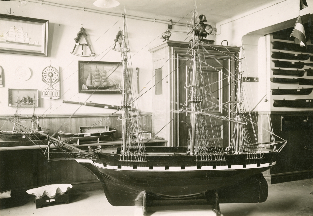Utställning från museets första utställningslokal i Sjöfartsmuseet, Skeppsbron 46, Stockholm. Interiörbild med fartygsmodeller m.m.