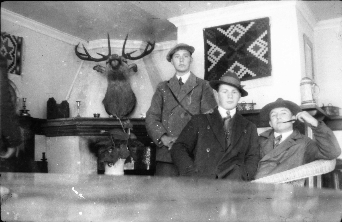 Tre unge menn med yttertøy i en stue.