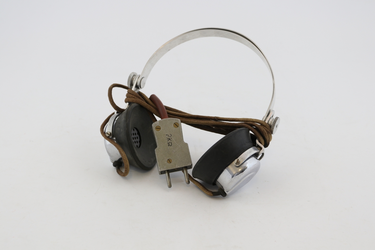 Øreklokker hovedsakelig av blankt metall, sorte gummi klokker mot ørene, fastkoblet til brun ledning med metallstøpsel. Størrelsen på bøylen kan reguleres litt ved hjelp av skruer og skinne på hver side.