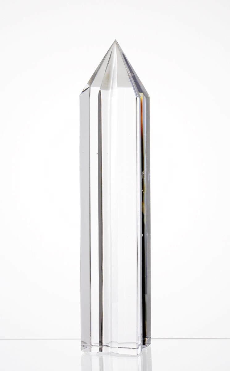 Glasskulptur "Axis" bestående av en planslipade obelisk, varav två sidor slipats med ett skär från topp till botten.