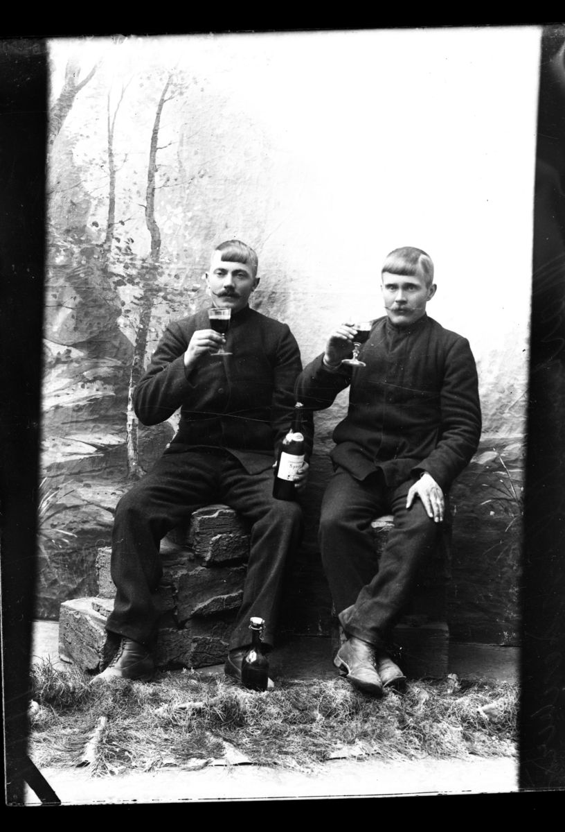 Atelierfoto. To menn sitter og drikker.