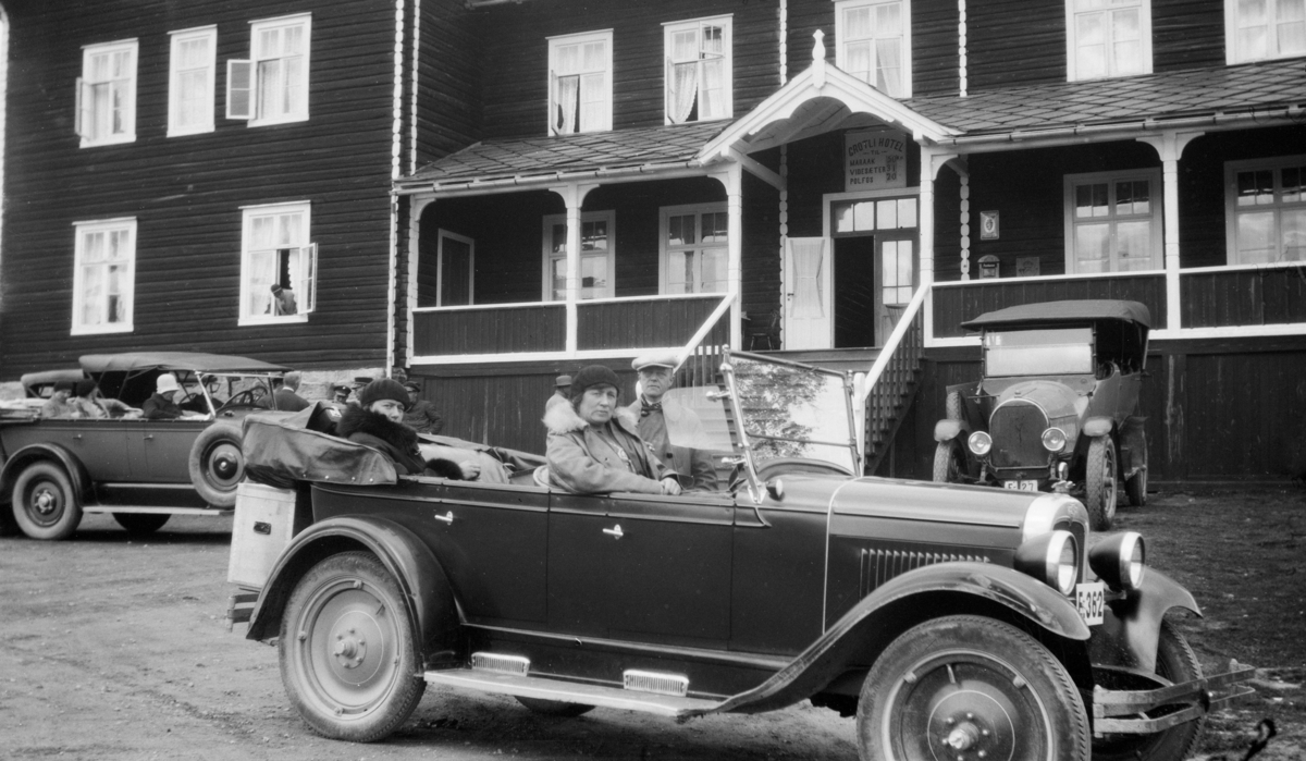 Biler og flere personer samlet utenfor Grotli hotel. Den nærmeste bilen er E-362, en Chevrolet 1927