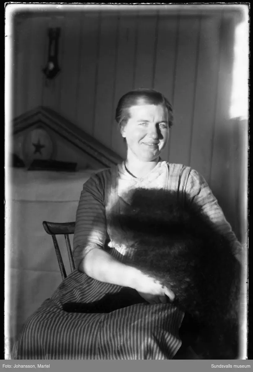 Porträttfoto inomhus av fotografens syster Märta Johansson med en hund i knät.