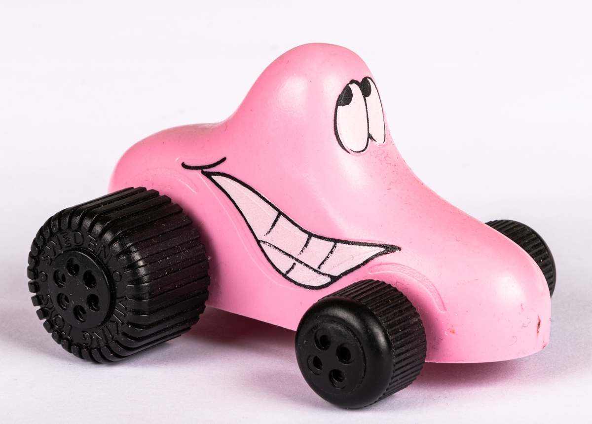 Leksaksbil, plast, rosa med svarta hjul. Formad som en Ahlgrens-bil.