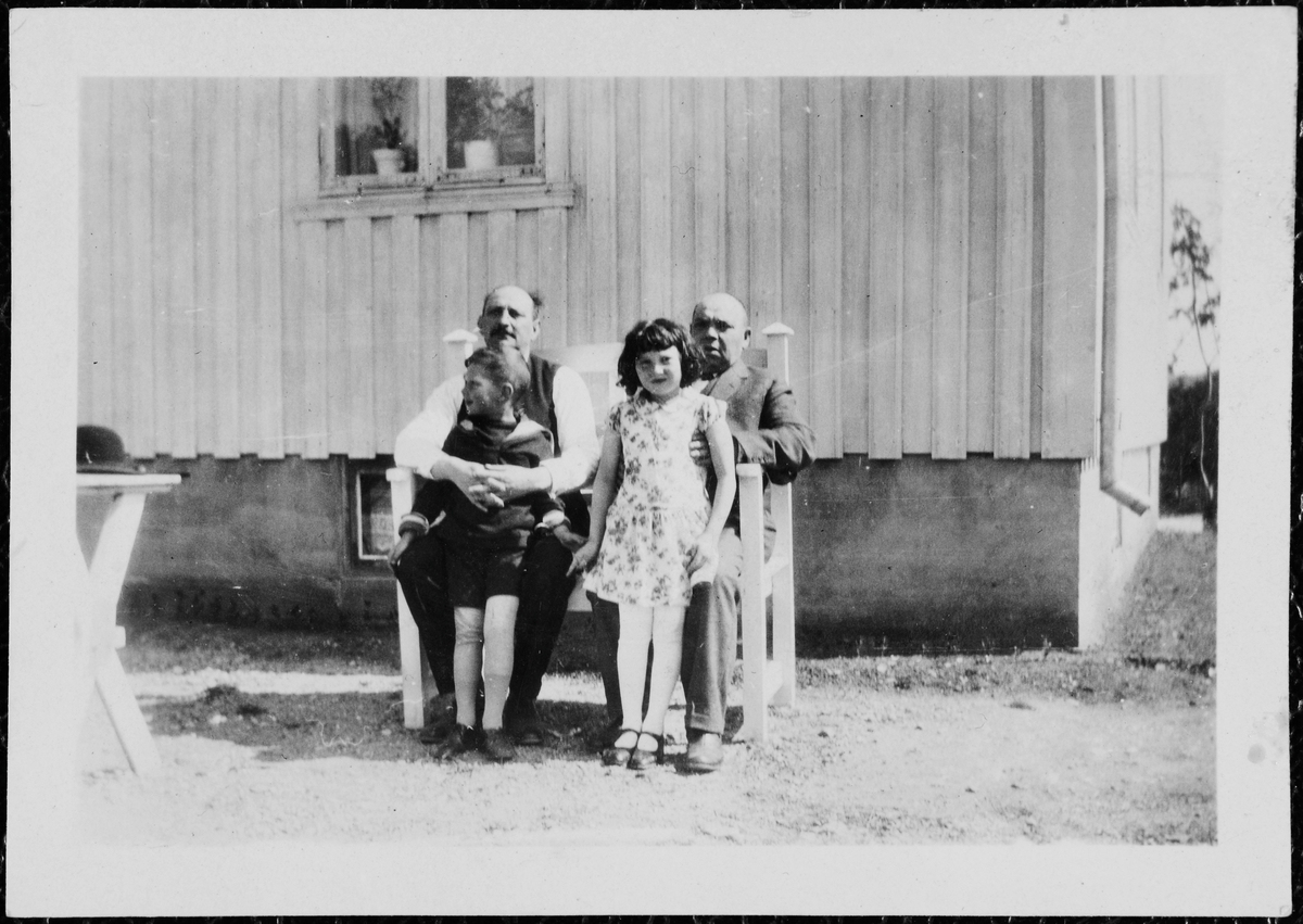 Moses Bekker, Adolf Bekker, Edith Bekker og Jakob Jacobsen utendørs på benk i en hage.