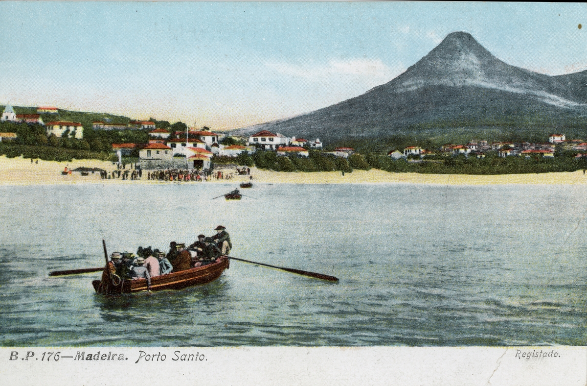 Vykort med motiv från Madeira, Porto Santo. Roddbåt med passagerare. I bakgrunden strand och bybebyggelse samt berg.