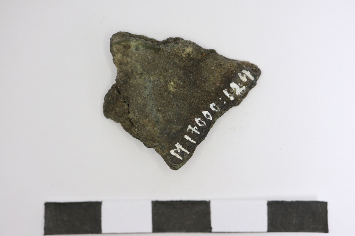 Brandskadat fragment av bronsgryta. Bukbit med eventuell skuldra.