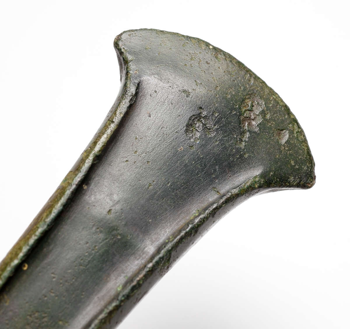 Kantyxa av brons med markerade kanter samt utsvängd och facetterad egg. Även sidorna är mjukt facetterade.