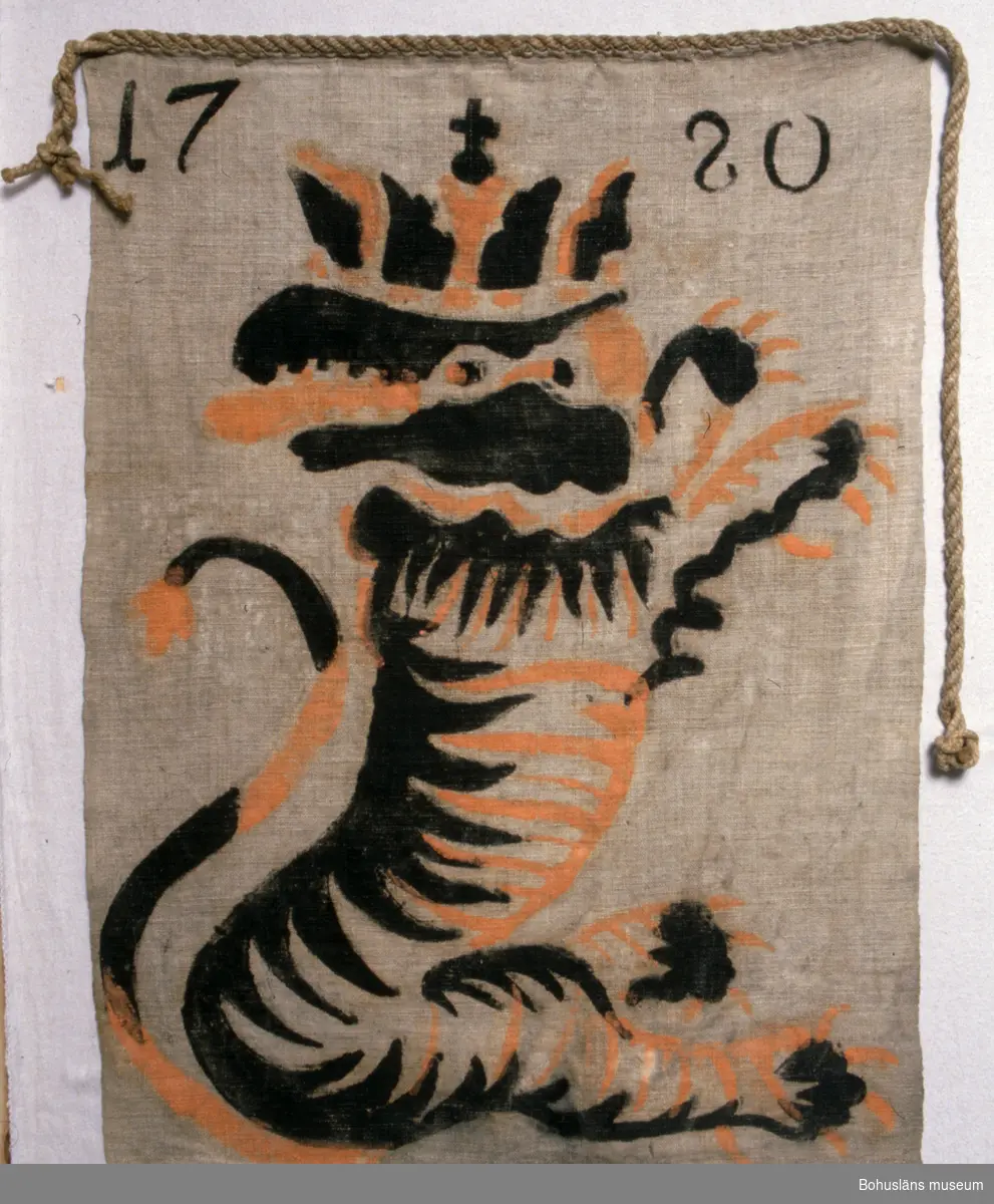 Lapp av oblekt, tuskaftvävt linnetyg. Med schablonmålad bild av heraldisk tiger (eller lejon?) med krona på huvudet i svart och rödgult (orange) samt årtalet "1780" i svart. Nertill fållad. Upptill fastsytt rep av hampa.
Från Halle- och Hunneberg, Västergötland. Jaktlappar användes vid sk drev- och skalljakt för att avgränsa jaktplatsen och för att skrämma villebråd, mest älg och rovdjur som varg och björn.
Upp till 60 meter långa rep med jaktlappar finns på länsmuseet i Skara. De har varit använda vid det kungliga hovets jakter under 1800-talet i Edsmärens kronopark i Västergötland.
