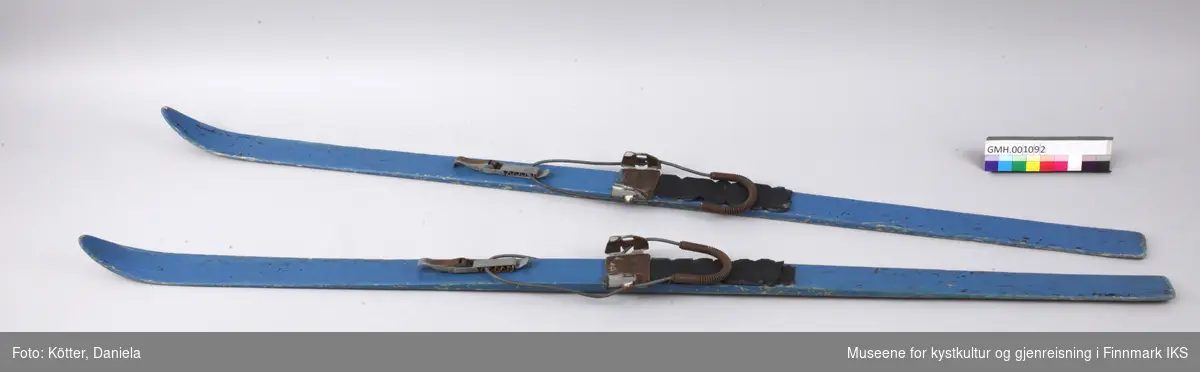 Blåmalte treski med Kandahar-bindinger. På området der skoene møter skiene, er det spikret på svarte gummimatter. 