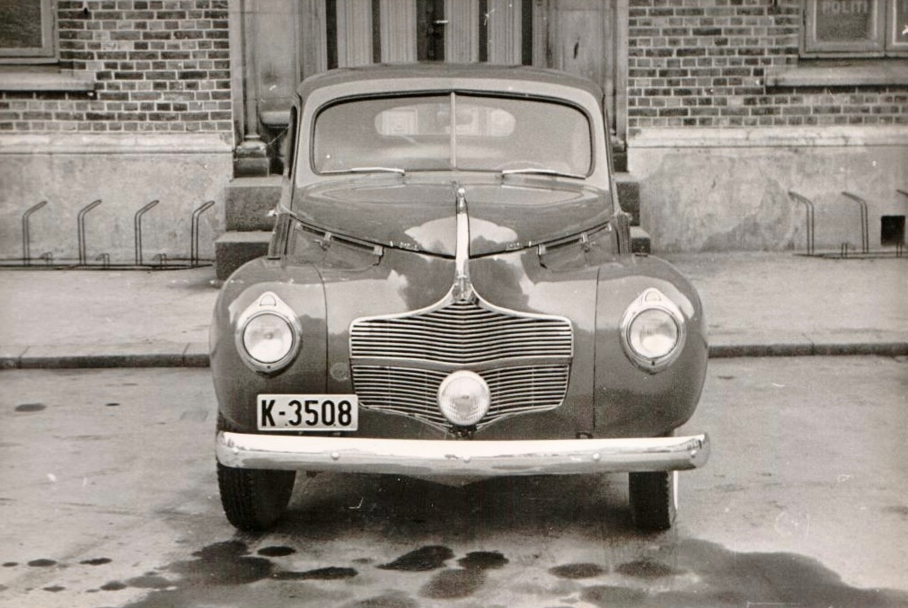 Sivil personbil Dodge 1939-40-modell med registreringsnummer K-3508 parkert foran en bygning. Bilen er fotografert både forfra og fra siden.