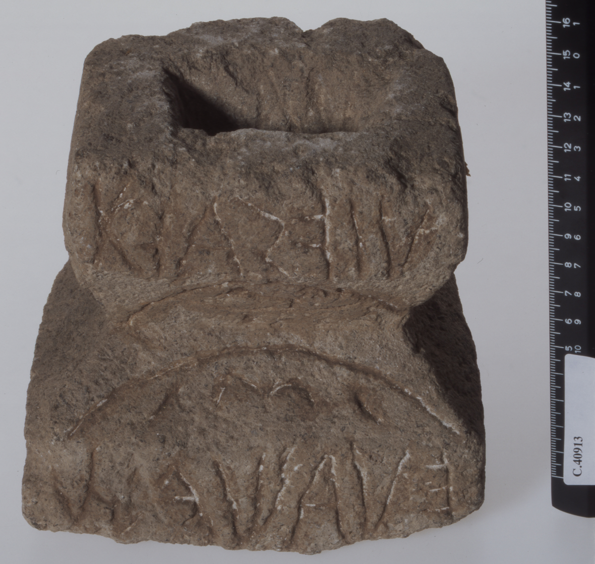 Rectangular base with notch dividing it into an upper and a lower part. Rectangular hole in top surface.  Etruscan inscription on  upper and lower vertical front sides; incised decorations above and below the inscriptions. The cippus part belongs to C 41765. Good condition.
