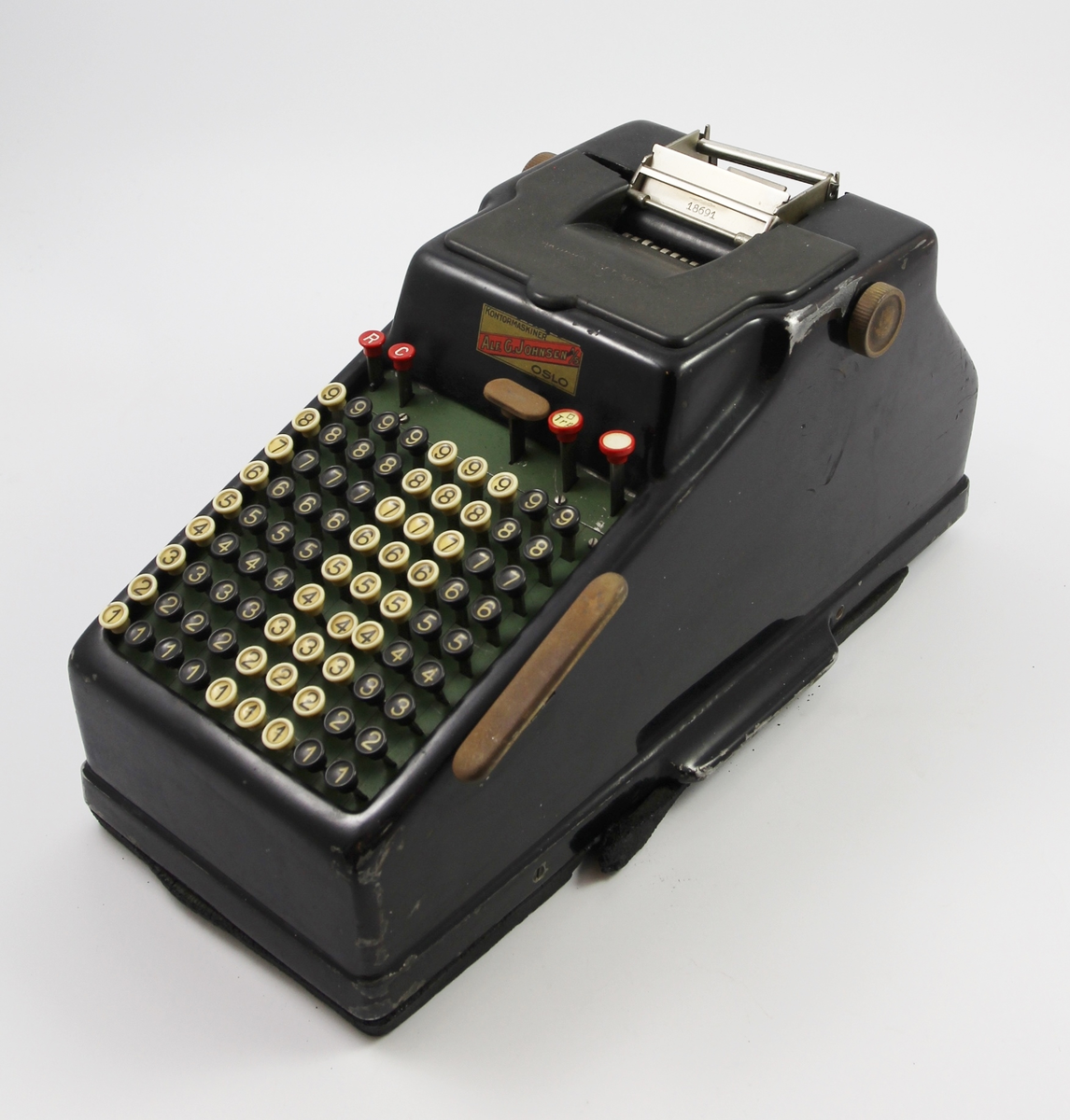 Sort skrivemaskin, kun med tall. Rektangulær from med svakt skrånet tastatur mot en av kortsidene.