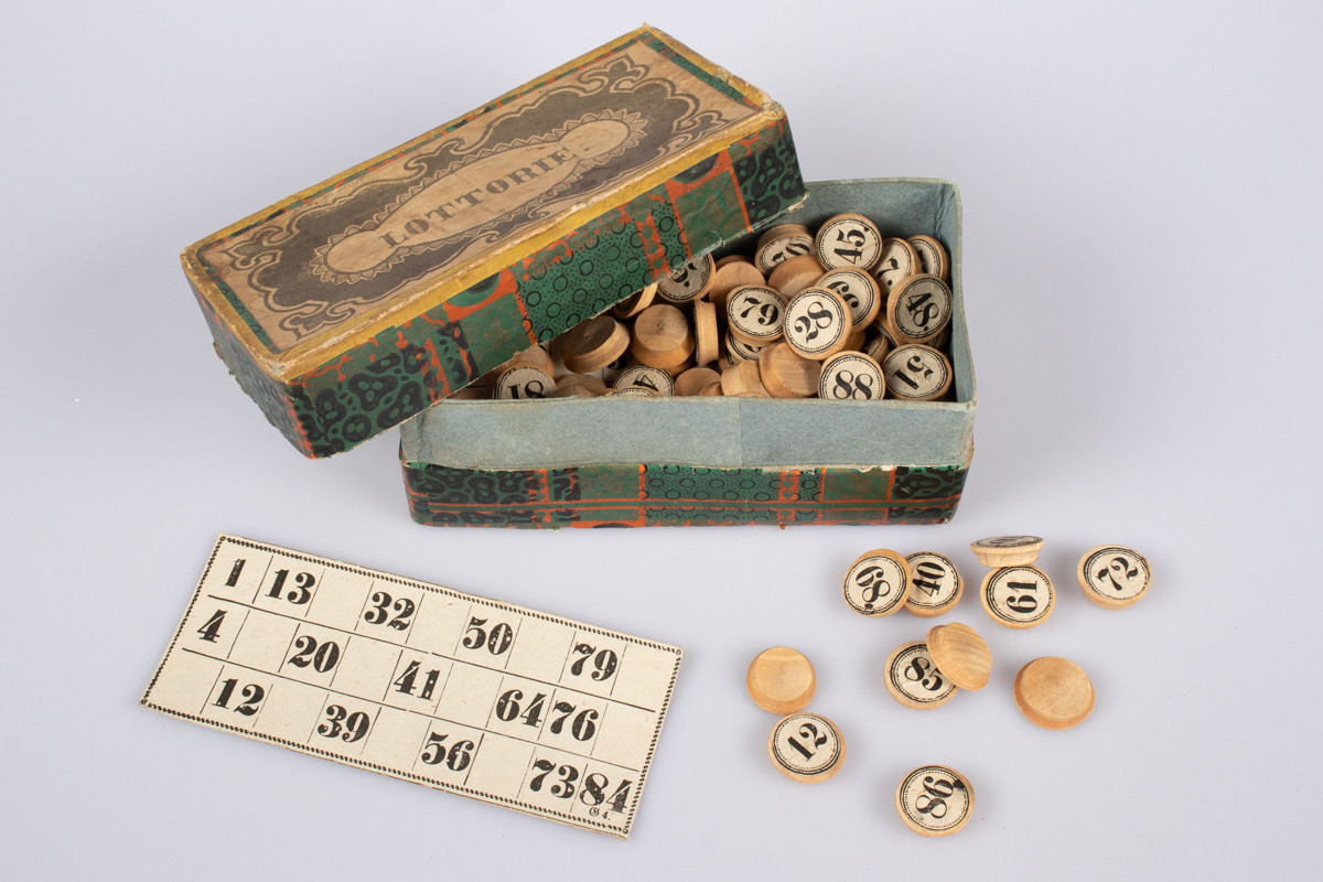 Eske i kartong med brikker og kort med tall på for å spille lotteri eller bingo