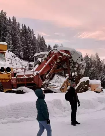 Bildet viser besøkende ute om vinteren med store maskiner bak seg.