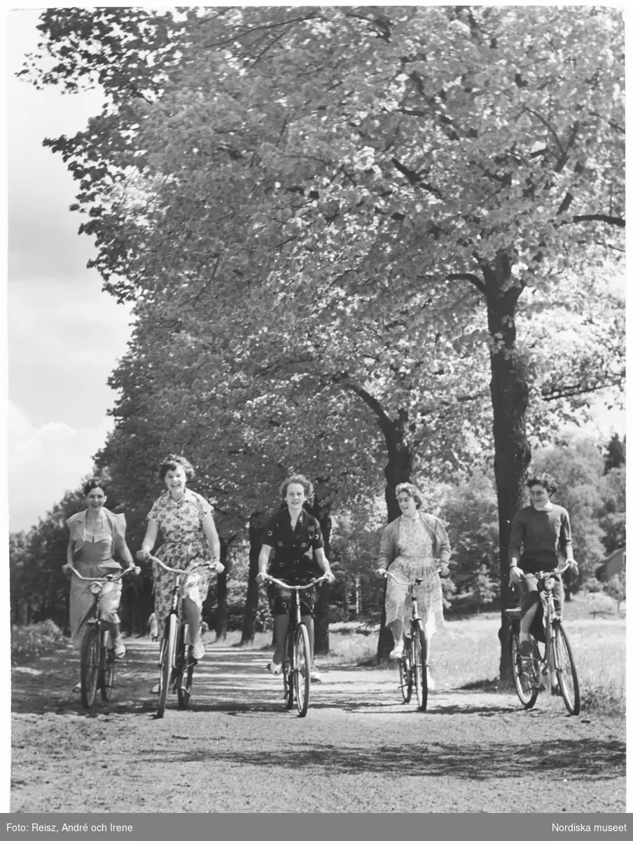 Fem unga kvinnor cyklar genom parken.