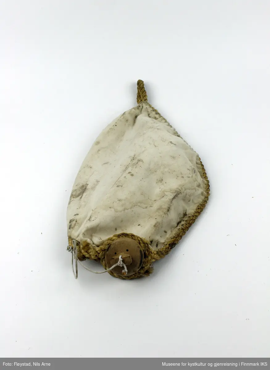 En oval bølgedemper, eller oljepose laget av lerret og sydd sammen med hampetau. Det er festet en trekork til å åpne og lukke posen. Trekorken er festet til en hvit tråd.