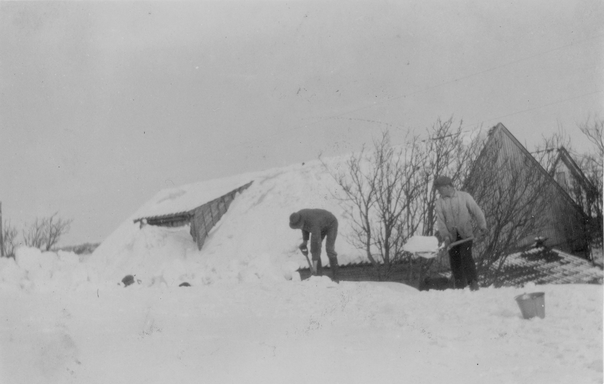 To menn måker snø av taket på ei bygning.
