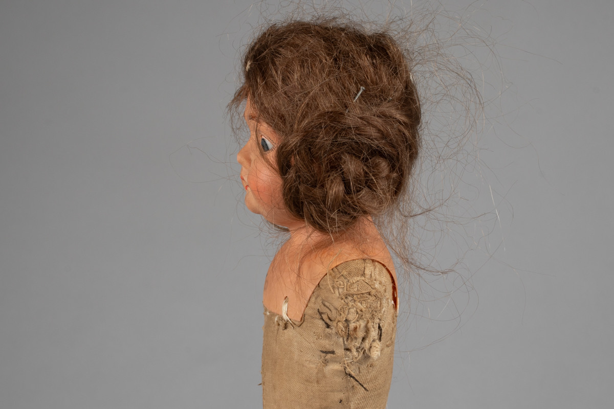 Dukke med  tett stoppet tøykropp. Tøykroppen er fra 1882, da dukken ble kjøpt ny. Den er reparert flere ganger, og nye tøystykker er montert på. Hodet og armene var opprinnelig av porselen, men de ble ødelagt i lek. I 1919 arvet Dorotheas datter dukken, og i den sammenheng fikk den nytt hode i det moderne stoffet celluloid. Dukken har øyne som kan åpnes og lukkes, og langt brunt hår i fletter.