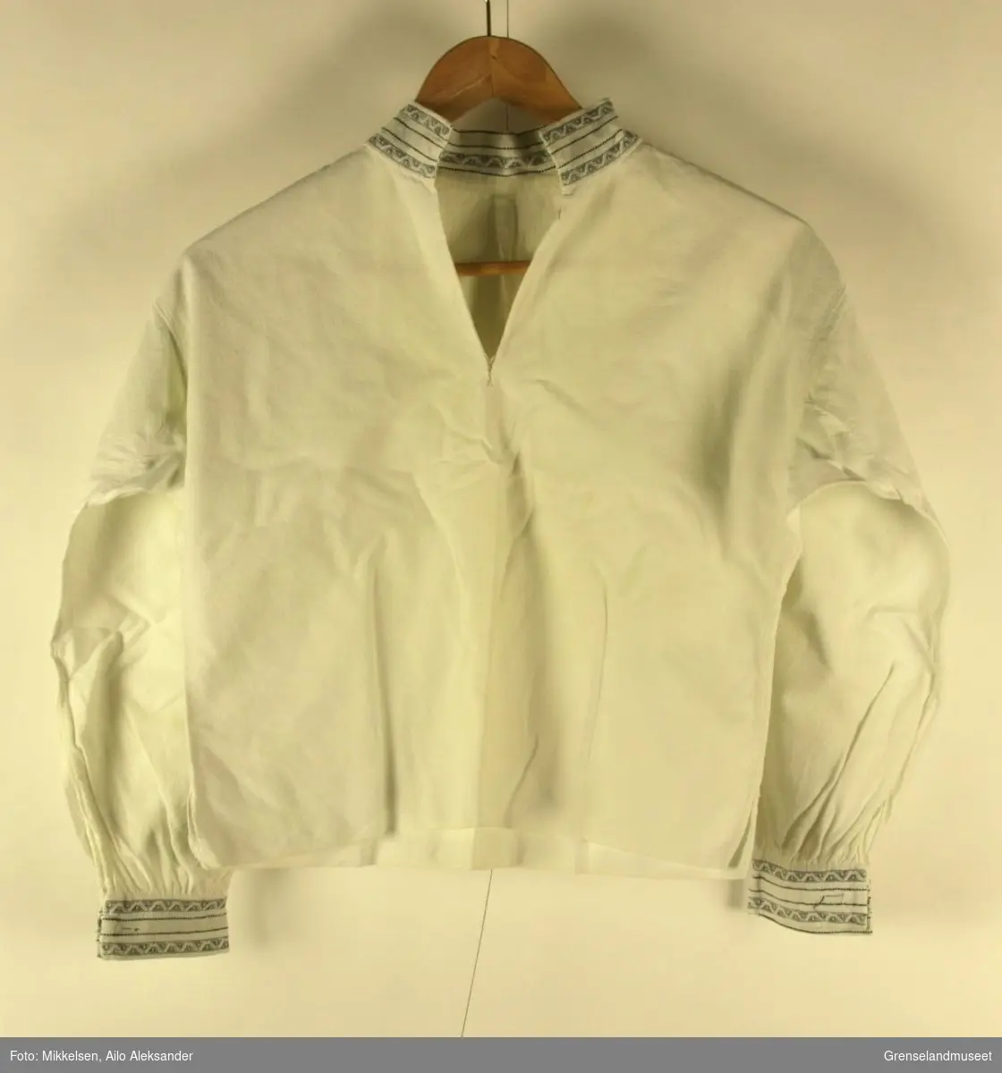 Gjenstandene er en hvit skjorte som har vært i bruk av Bjørnevatn Pikekor. Kragen og ermene er dekorert med sydd mønstersøm i hvitt og svart.