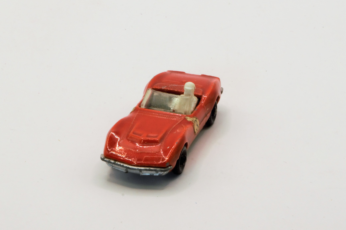 Rød lekebil fra 60/70-tallet. Produsert i England. Corvette, rød sportsbil med sjåførfigur.