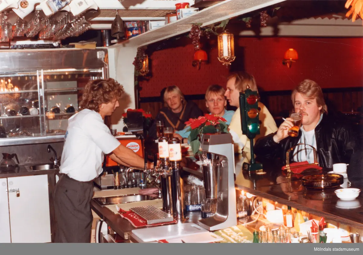 Robert Säll serverar gäster i baren på Moulin Rouge, restaurang och diskotek med adress Kvarnbygatan 1 i Mölndal, år 1988.