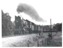 Damplokomotiv type 30a med persontog kjører ut fra Hamar sta