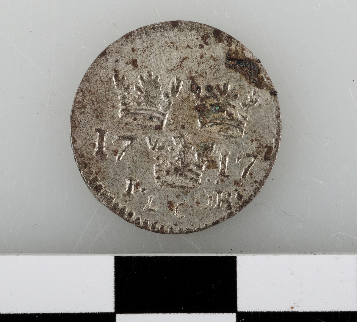 Mynt av silver. 1 öre 1717 (Karl XII), präglat i Stockholm.