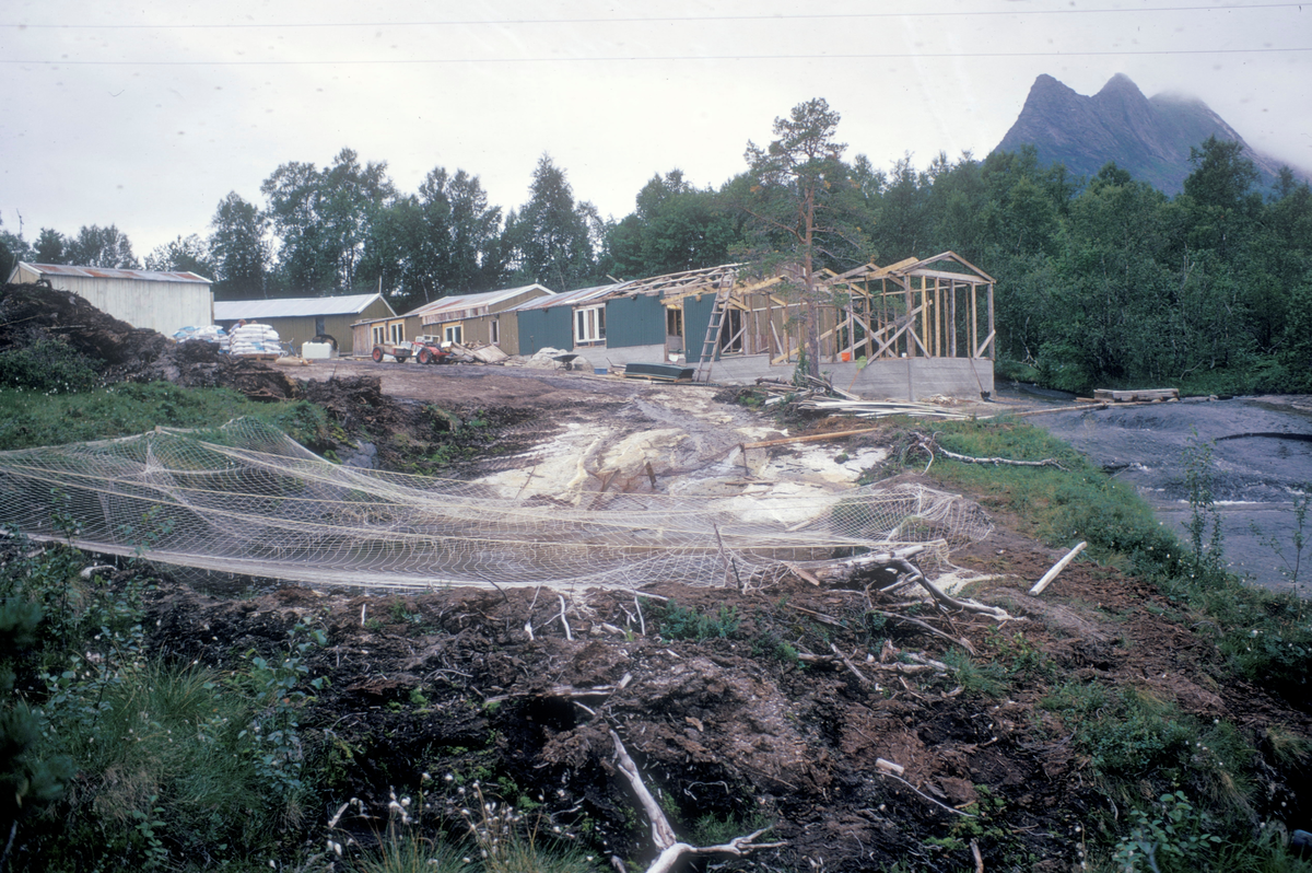 Oppdrett, Kristiansen H. : Bygninger under konstruksjon. I forgrunnen ser vi en vanndam med netting over.
