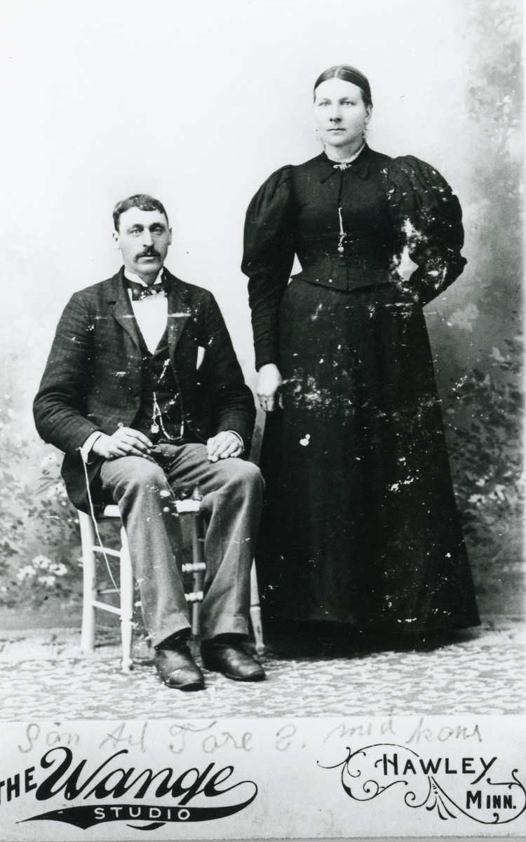 Portrett av mann med bukse,jakke,sløyfe og klokkekjede Dame med kjole.