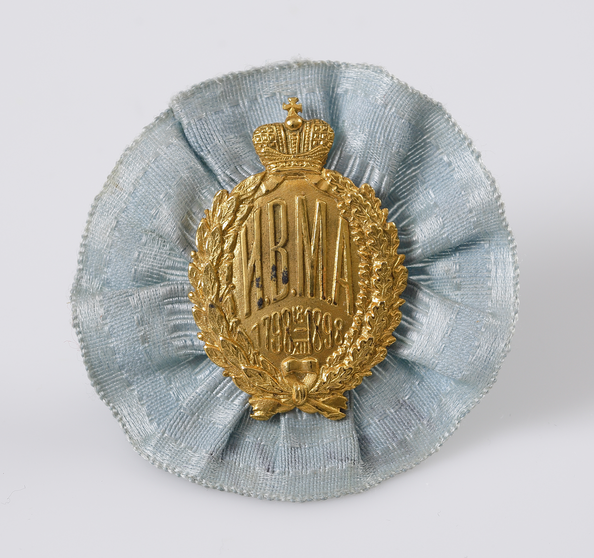 Kotiljong/brosch i ljusblått siden och pressat emblem i gul metall med text; "HBMA 1798 18/XII 1898", under rysk kejserlig krona.

Inskrivet i huvudbok 1969.