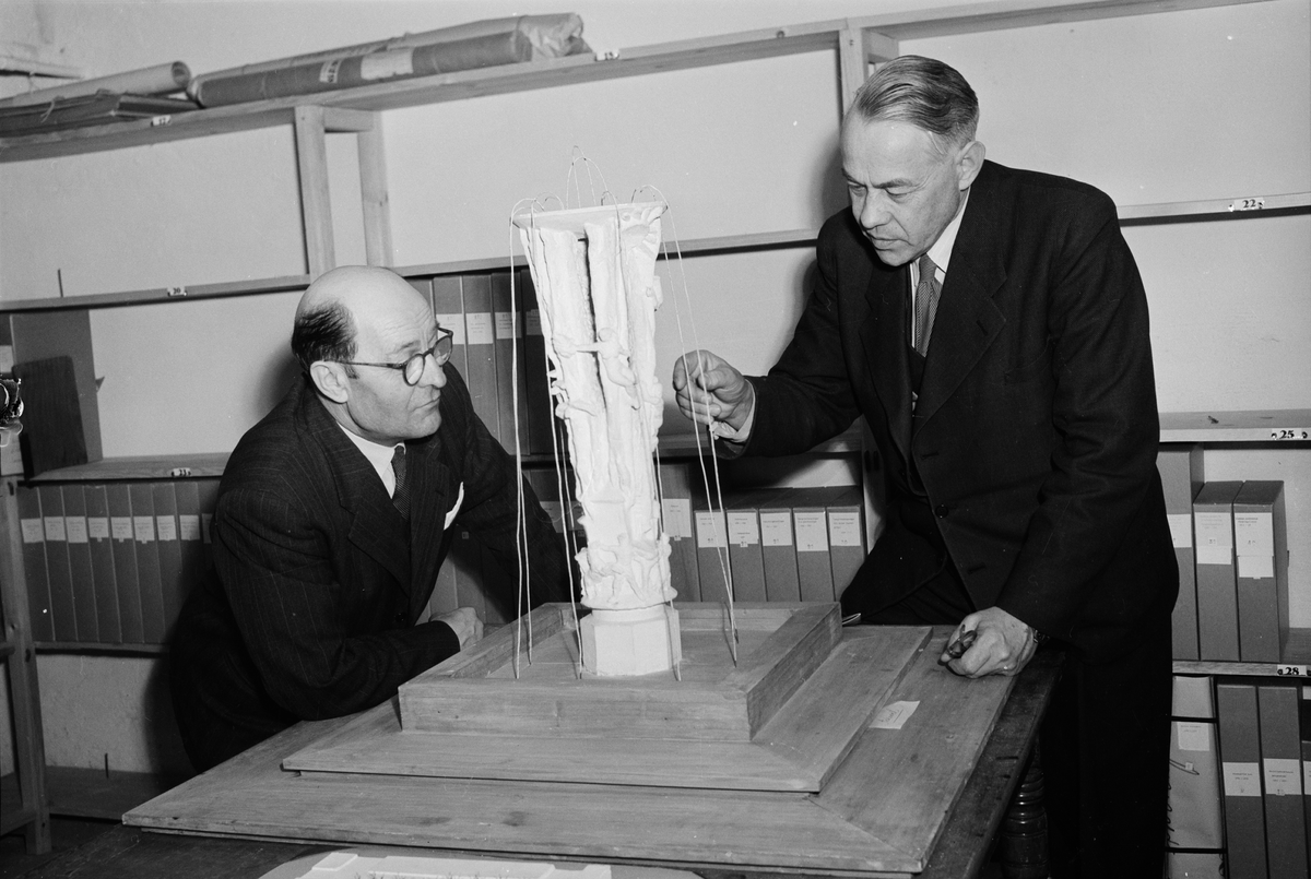 Två herrar beskådar byggmodellen av "De fyra elementens brunn".