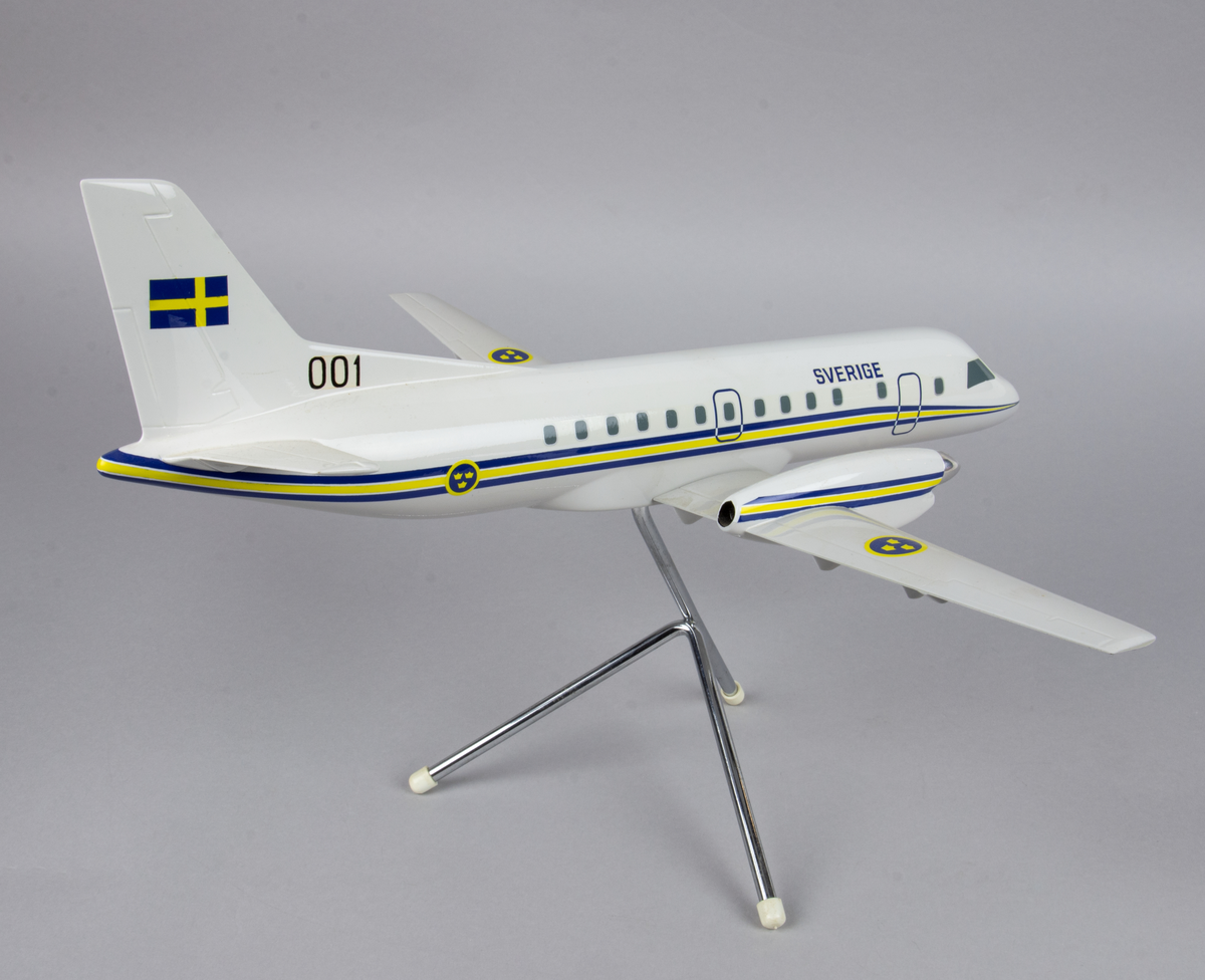 Flygplansmodell, TP 100A, SAAB 340B, nr 100001.
Modellen är märkt med texten Sverige på sidan av framkroppen, 001 och en svensk flagga på fenan samt dekaler med kronmärken på vingarna. Längst hela kroppen en blå och gul linje. Modellen står på ett bordsstativ av metall.