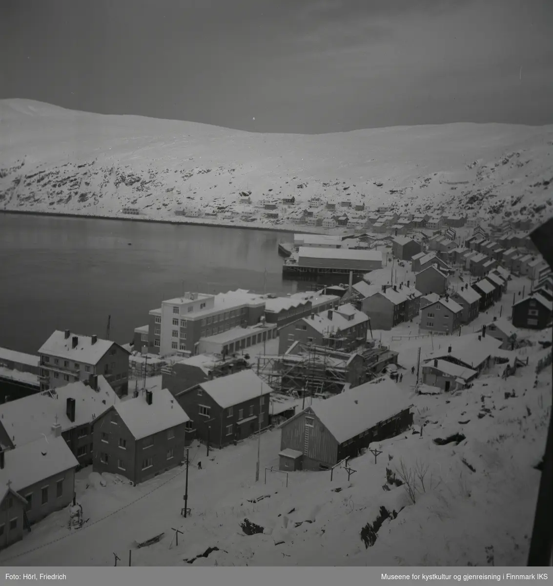 Oversikt over deler av Hammerfest sentrum og Molla i vinteren 1957/1958. Bildet er fotografert fra Salenfjellet. Sentralt i bildet ser man den katolske kirke St. Mikael som bygges. Ved havna ser man også byggene til Findus og Hauans materialhandel.