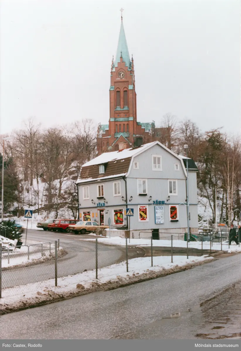 Järnhandlarerondellen i Mölndals centrum i januari 1984. Joel Jacobsons järnhandel med adress Frölundagatan 30. I bakgrunden Fässbergs kyrka.