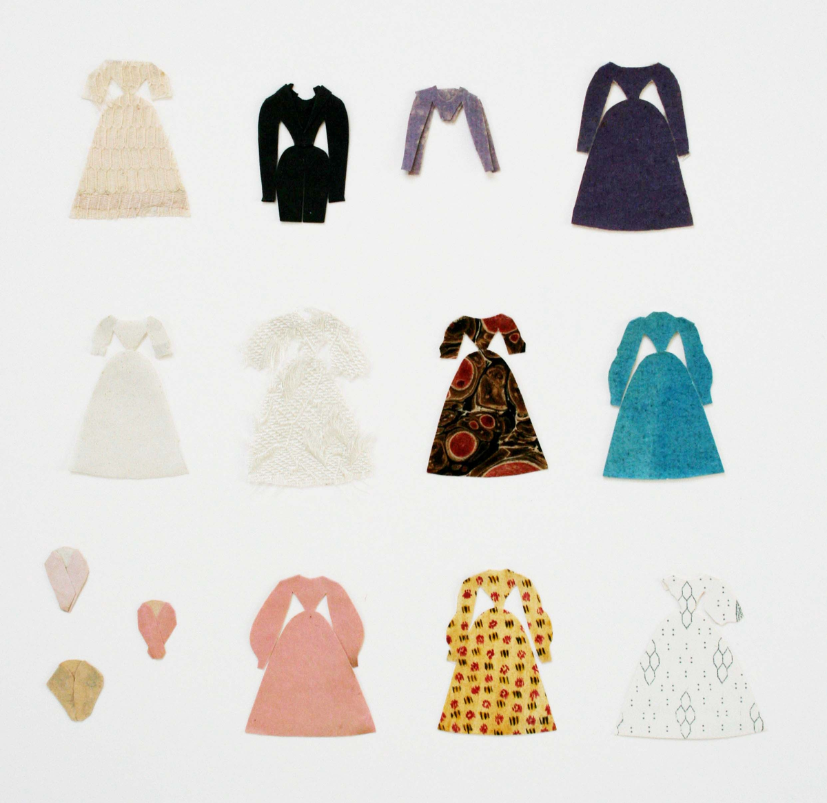Dockor med små huvuden. Kläder klippta av olika slags enfärgade och mönstrade papper (tryckta, handmålade). Kläderna har smala midjor, vida kjolar och ärmar.

Herrkläder: kostymer, rockar.

Damkläder: klänningar, blusar, kjolar, sjalar och halsband. I cellofanmappar.

1. 3 män, 2 kvinnor, påklädda +1 rock, 14 klänningar, 1 kjol, 1 förkläde, 4 sjalar och 2 halsband.

2. 34 klänningar.

3. 10 klänningar, 1 blus, 3 sjalar.

4. 42 klänningar, 1 blus, 1 byxa, 10 sjalar.

5. Påklädd man + 3 rockar, 1 blus, 1 jacka, 5 klänningar, 2 kjolar, 5 sjalar. Låg i litet kuvert märkt "Maris dockor".

6. 11 kjolar, 2 blusar, 13 sjalar.

7. 20 fyrkantiga sjalar, de flesta med klippt frans. Låg i vikt papper märkt "Anguelie".

8. 13 fyrkantiga sjalar varav 9 med klippt frans, 3 små sjalar, 1 klänning. Låg i vikt papper märkt "Marias".

9. 6 små sjalar, 1 halsduk. Låg i liten svart och guldfärgad pappask tillsammans med litet brev från "Albertina".