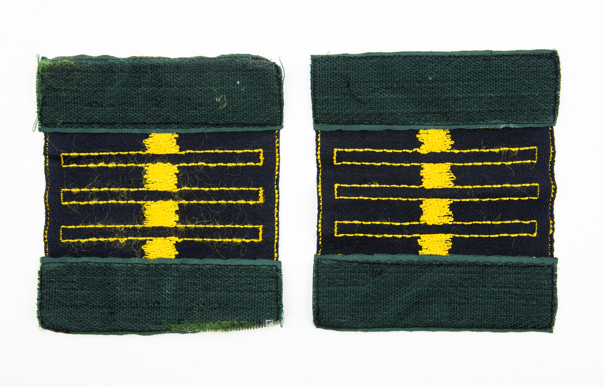 Ärmmatta, överstelöjtnant, med invävd gradbeteckning i gult på svart botten. Två stycken. På baksidan fastsydda kardborreband.