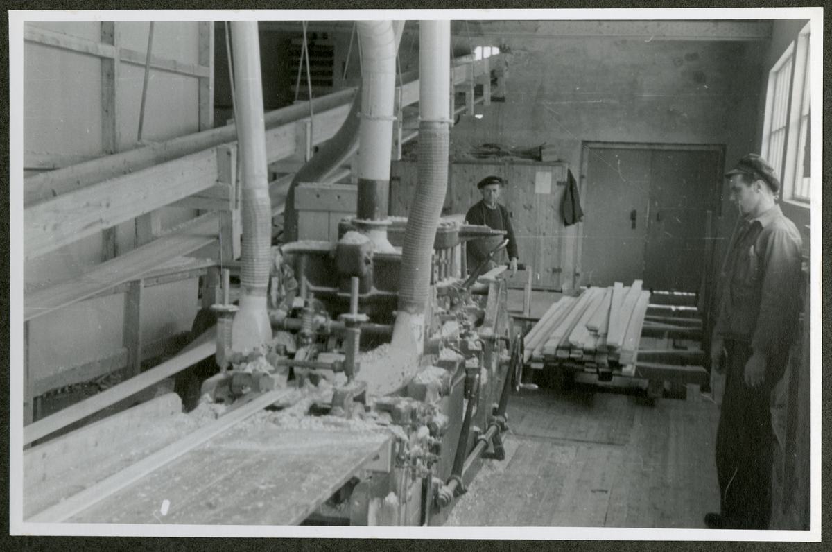 Foto av tremateriale og arbeidere ved maskineri ved Aall-Ulefoss Brugs Dørfabrikk
