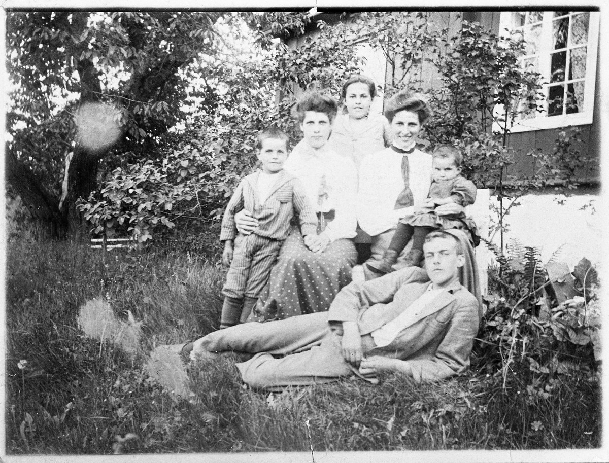 Medlemmer av familien Raabe avbildet på Evenrud på Kapp, Østre Toten, ca. 1904. Personene: Sverre Raabe, Ragnhild Schultz (f.Raabe), Pauline Hveem (f.Raabe), Henny Bergsland (f.Raabe) med Aagot Sveinson (f. Raabe) på fanget,. Liggende foran er Frantz Raabe.