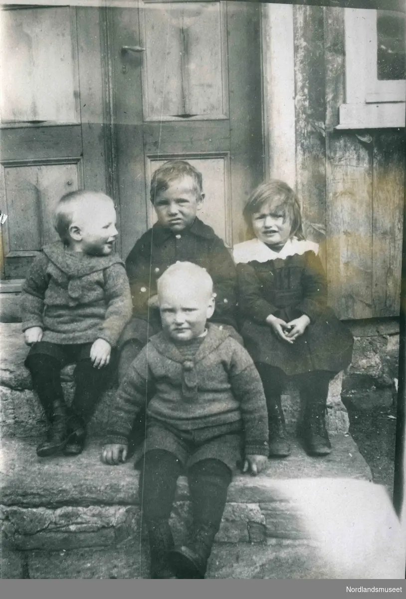 Fire små barn sitter på en steintrapp.