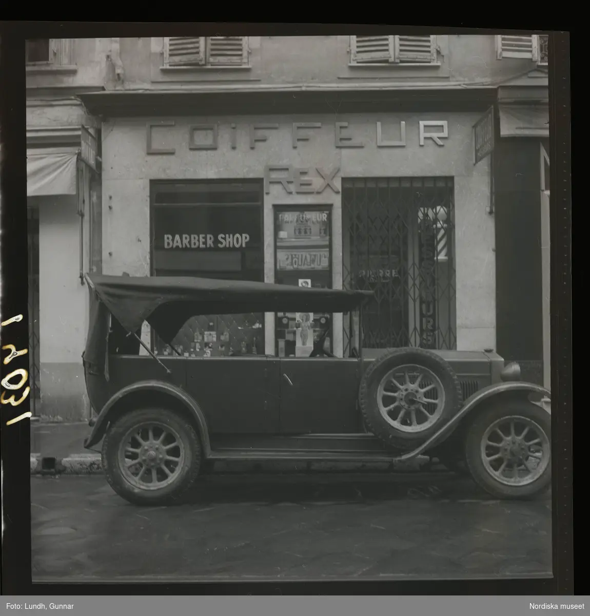 1950. Frankrike. Bil parkerad utanför en frisörlokal