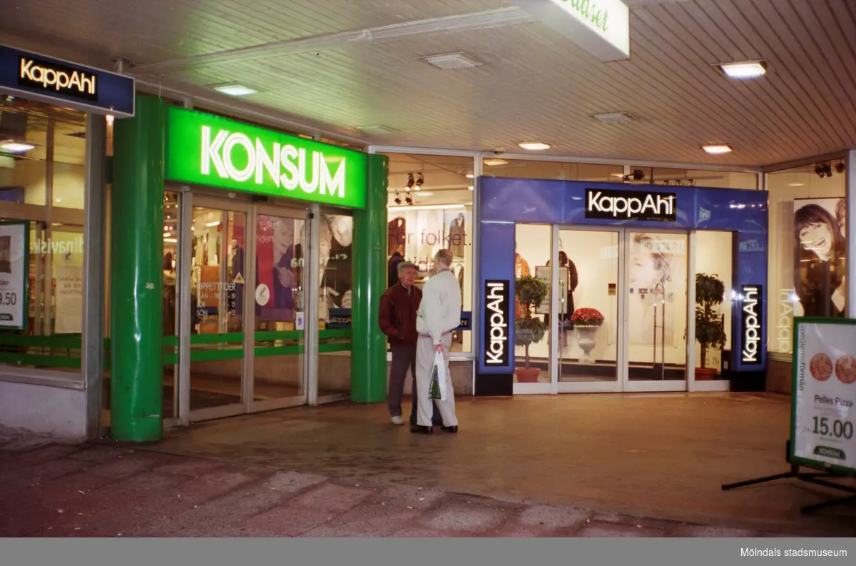 Konsum och KappAhl på Brogatan. Mölndalsbro i dag - ett skolpedagogiskt dokumentationsprojekt på Mölndals museum under oktober 1996. 1996_1212-1226 är gjorda av högstadieelever från Kvarnbyskolan 9D, grupp 5. Se även 1996_0913-0940.