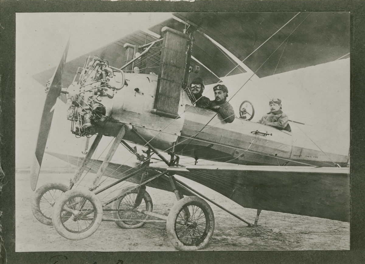 Flygplan B 1, Bréguet C.U 1 med tre flygare står på ett flygfält, omkring 1912. Avfotografering av monterat foto.