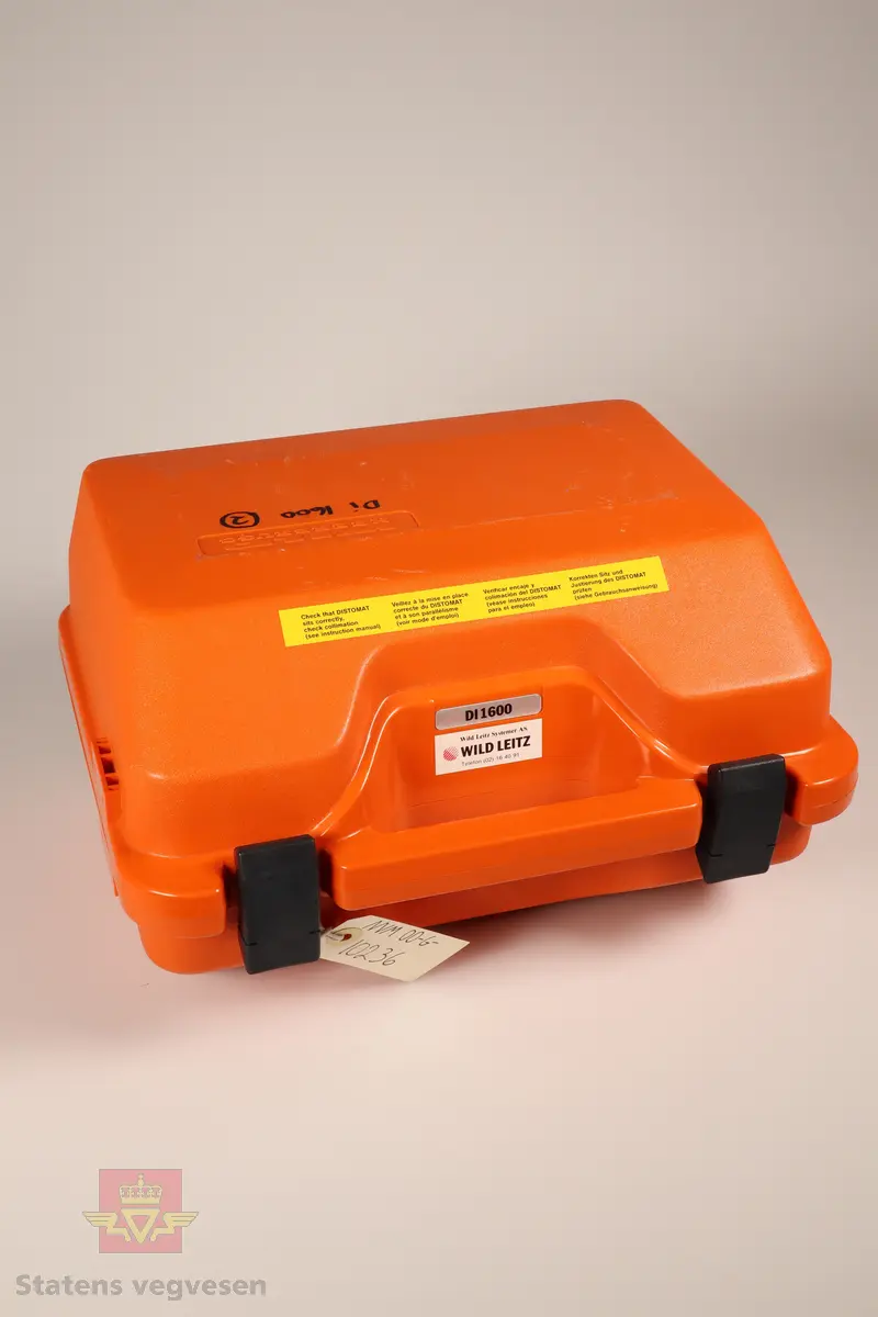 En oransje beholder som inneholder en elektronisk avstandsmåler av typen DISTOMAT WILD DI1600, et eksternt batteri, ti ekstra sikringer, en LEMO kabel og en unbrakonøkkel. 
