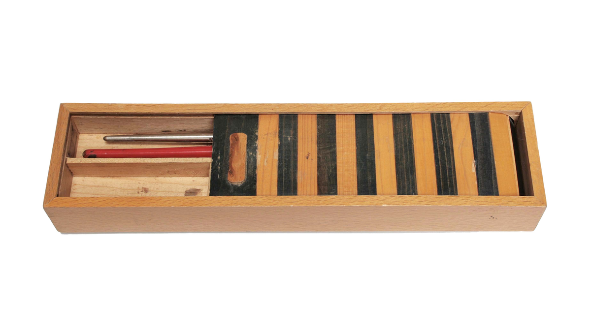 Rektangulärt skrin med 3 fack. Lock av jalusi, randigt i ljusbrunt och svart. Innehåller: 1 rött pennskaft av trä och 1 skaft av metall med pressad bladdekor, eventuellt för ritkol.