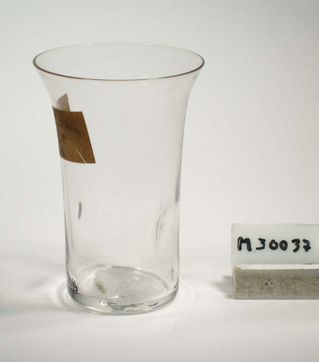Cylindrisk kupa, utsvängd mot mynning. Fyra inbuktningar långt ner på glaset.
