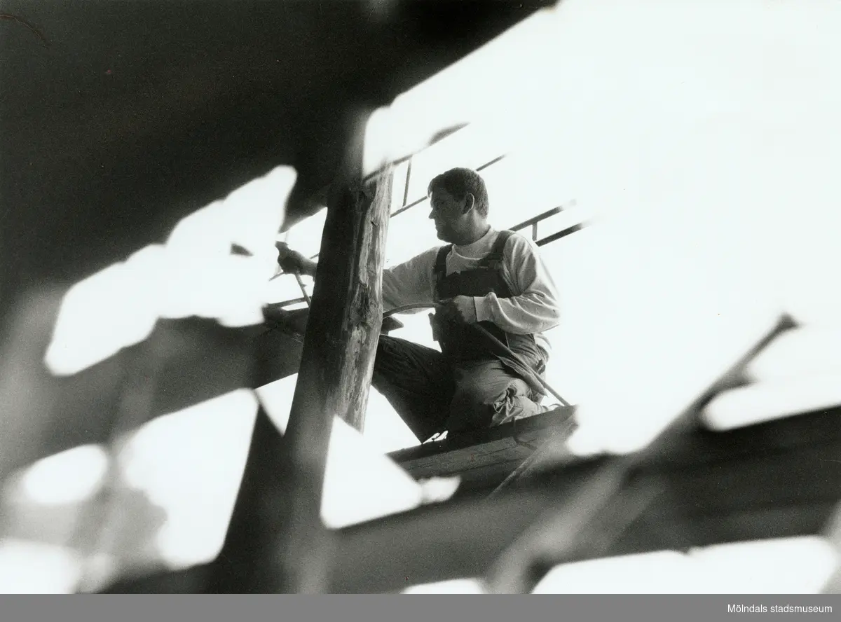 Nya Teaterhuset byggs upp 1997 - 1998. Närbild på en person som är tagen snett framifrån. Personen står utomhus på en byggnadsställning och arbetar med huset.