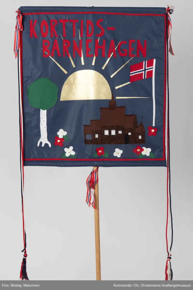Mørkeblå bakgrunn. Rød skrift, dekorert med en sol, Høyjord stavkirke, norsk flagg, tre og blomster.