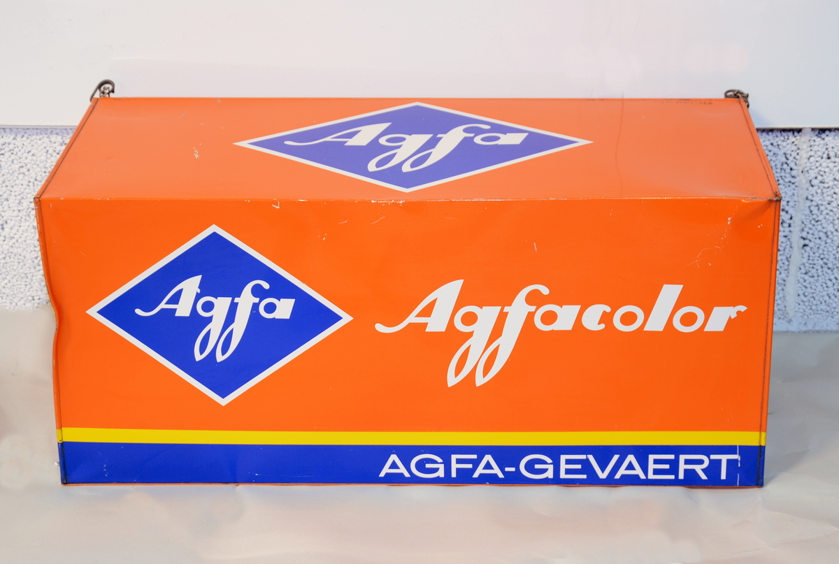 Reklame for Agfa, formet som en stor filmboks i metall med oppheng, til å henge opp på utsiden av fotobutikken.